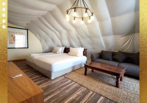 拉斯阿尔卡麦Desert Breeze Cocoon的一间卧室配有一张床,一张沙发位于帐篷内