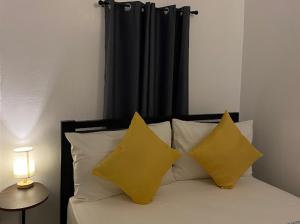 SorsogonDreamink farm og Myl`s place的一张带两个黄色枕头和黑色窗帘的床