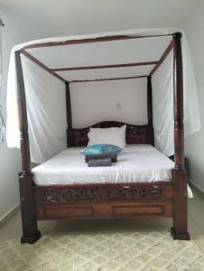 GaluDiani Hideaway Beach Villa的一张带木天蓬床和枕头的床