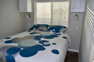 萨拉索塔Pinecraft Blue Heron Tiny Home的一间卧室配有一张带蓝色和白色棉被的床