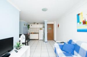 福塔莱萨Iracema Apartament的一间带蓝色沙发的客厅和一间厨房