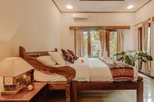 登巴萨Villa Nelayan Sands的一间卧室设有一张木床和一个窗户。