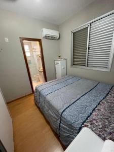 贝洛奥里藏特Apê na Pampulha 3Q, Ar Split, Churrasco e 2 Vagas的一间卧室配有一张床,窗户配有空调
