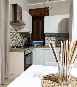 皮耶特拉佩尔托萨Pietrapantone B&B的厨房配有白色橱柜和带木筷子的桌子。