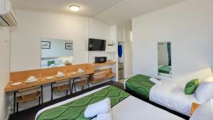 格伦因尼斯CBD GI Motel的酒店客房配有两张床和一张书桌
