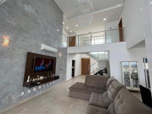 瓜拉廷格塔Quartos privativos - Casa de alto padrão的客厅配有沙发和墙上的电视