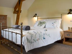 NorthleighBucknole Farm - The Old Shippon的一间卧室配有带白色床单和枕头的金属床。