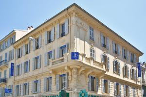 尼斯Hôtel Le Seize, Nice Centre的一座白色的大建筑,上面有蓝色的标志