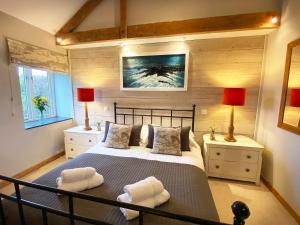 Crowan燕子谷仓乡村别墅的一间卧室配有一张大床、两盏灯和毛巾