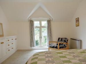 WhitwellElm Cottage的卧室配有床、椅子和窗户。
