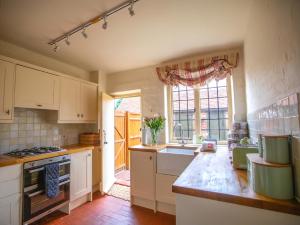 BensonDulcie Cottage的厨房配有白色橱柜、水槽和窗户。