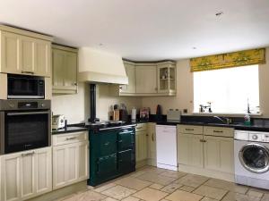 DunstallBrankley Cottage - E4712的厨房配有绿色和白色的橱柜和洗碗机。