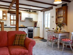 斯基普顿Mallards Nest的一间带红色沙发的客厅和一间厨房