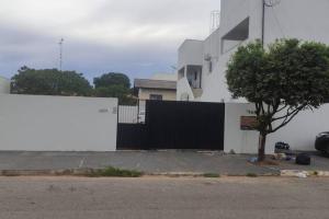 索里苏Apartamento Sorriso的白色的建筑,有黑色的栅栏和一棵树