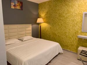 新山Fortune Hotel的卧室配有白色的床和黄色的墙壁