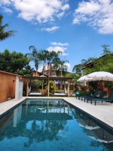 皮雷诺波利斯Confraria da Prata Flats的房屋旁的游泳池配有椅子和遮阳伞