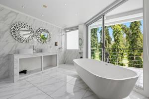 卡图The Fairways Villas - 5 bedrooms & bathroom for up to 14 guests 7kms to Patong的带浴缸的白色浴室和大窗户