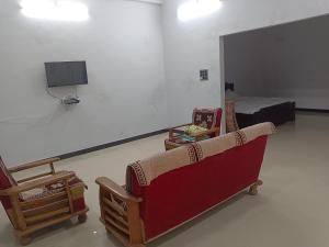 乌贾因Narayan nivas homestay的一间配备有沙发、电视和床的客房