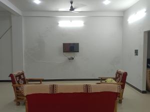 乌贾因Narayan nivas homestay的一间设有桌子的房间和墙上的电视
