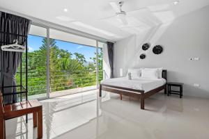卡图The Fairways Villas - 5 bedrooms & bathroom for up to 14 guests 7kms to Patong的白色的卧室设有床和大窗户