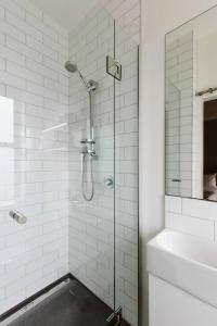 新普利茅斯斯塔特酒店的白色浴室内的玻璃淋浴间,配有水槽