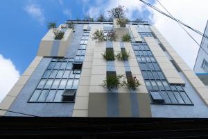 胡志明市Lanura Apartments and Hotel的一座高大的建筑,上面有盆栽植物