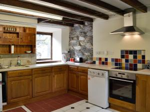 PenmachnoValley Cottage的厨房配有木制橱柜和白色洗碗机。