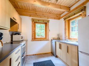 基林Larch的一间带木制天花板和白色冰箱的厨房