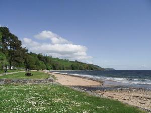 GlenurguhartThistle Lodge - Uk7051的海滩上有人坐在水边的长凳上