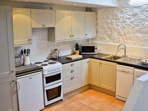 Crowan朗恩谷仓度假屋的厨房配有白色橱柜和白色炉灶烤箱。