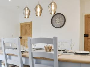 PakefieldSapphire Cottage的一张餐桌、白色椅子和墙上的时钟