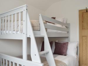 PakefieldSapphire Cottage的白色的客房设有白色的双层床,设有楼梯