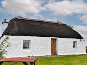 GramisdaleTaigh Violet Rose的白色的建筑,拥有茅草屋顶和木门