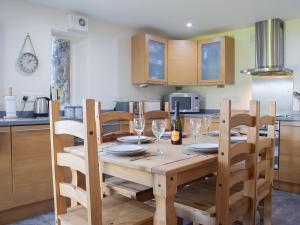 TalleyBarn Cottage的厨房配有木桌、带酒杯的椅子