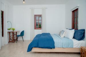 北碧Vawa Guesthouse的一间卧室配有一张带蓝色床单的床和一张桌子。