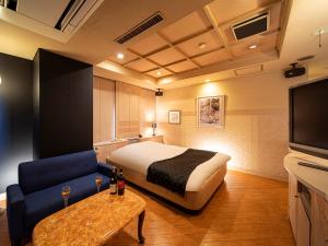 京都圣马丁酒店（成人专用）的酒店客房配有床、沙发和电视。