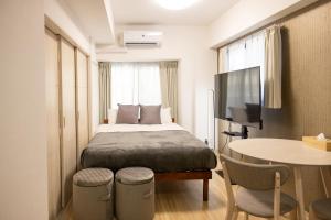 大阪Ocean Tsutenkaku的小房间设有床、桌子和电视