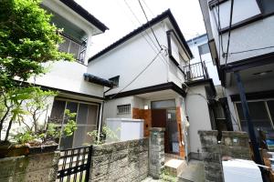 东京JH Yellow Guest House的前面有栅栏的白色房子