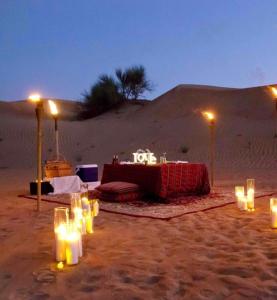 山姆Hilton Jaisalmer Desert camp的沙漠中的一张桌子,在沙子里放着蜡烛