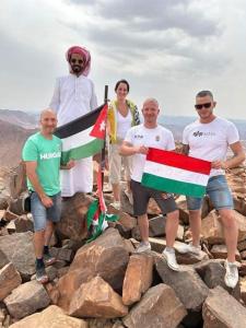 瓦迪拉姆Adam Bedouin camp的一群站在岩石上,举着旗帜的人