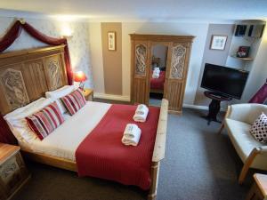 莱顿巴泽德The Heath Inn的一间卧室配有一张床、一张沙发和一台电视