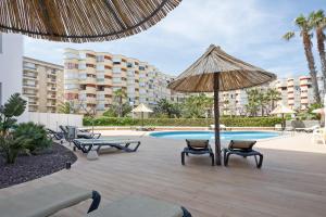 拉皮内达贝斯特拉马里纳酒店的一个带椅子和遮阳伞的庭院和一个游泳池