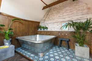 霍尔特Shirehall Apartments的浴缸位于一个种植了两盆植物的房间