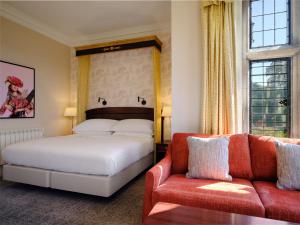 德比Delta Hotels by Marriott Breadsall Priory Country Club的一间卧室配有一张床和一张沙发