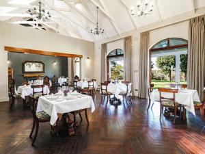 KingsmeadThe Peech Boutique Hotel Zimbabwe的一间设有白色桌椅和窗户的用餐室