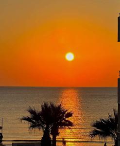 拉纳卡Hai Hotel的棕榈树环绕的海洋上方的橙色日落