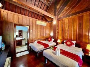 琅勃拉邦Lakhang Thong Hotel的木墙客房的两张床