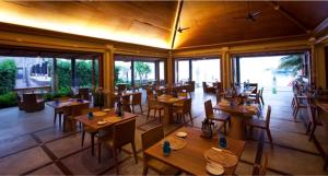 曾蒙海滩Deva Beach Resort Samui的餐厅设有木桌、椅子和窗户。