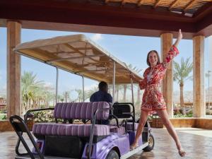 亚喀巴亚喀巴塔拉湾瑞享Spa度假酒店的一名妇女站在高尔夫球车上