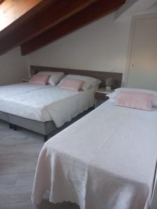 RicciaIl Riccio home & relax的卧室内的两张床,配有白色床单和粉红色枕头